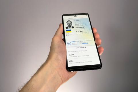 Dłoń trzymająca smartfon z otwartą aplikacją przedstawiającą dokument tożsamości