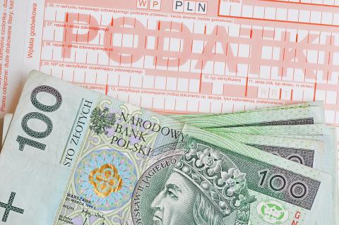 Plik banknotów stuzłotowych leżący na druku podatkowym