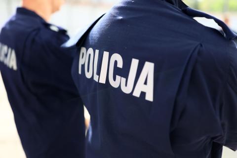 Dwie osoby w granatowych mundurach z napisem POLICJA na plecach