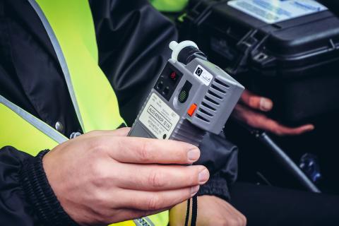 Dłoń policjanta służby drogowej trzymająca alkomat