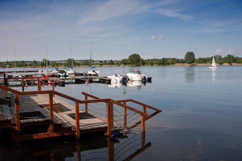 Pomost i przystań z kilkoma zacumowanymi jachtami nad zbiornikiem wodnym. 