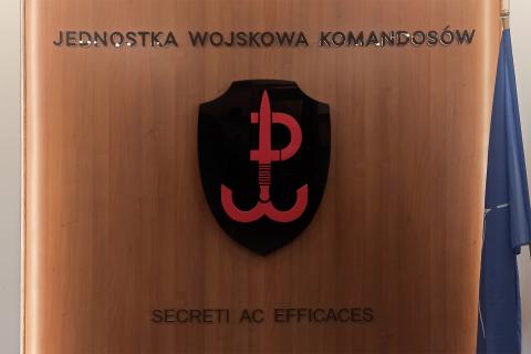 Ściana z symbolem jednostki wojskowej, obok której stoi flaga NATO