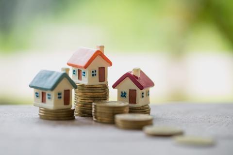 Figurki domków stoją na stosach ułożonych z monet