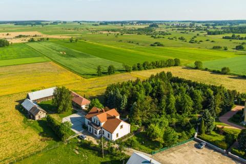 widok z lotu ptaka na zabudowania, pola i las 