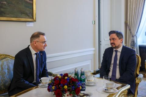 Dwie osoby w garniturach siedzą przy stole i rozmawiają