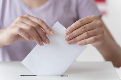 Osoba wrzuca kartkę do urny wyborczej