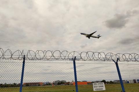samolot startujący z lotniska widzianego przez płot 