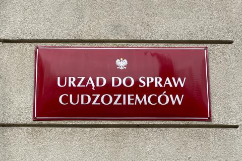 Przykręcona do elewacji budynku tablica z godłem Polski - orłem w koronie - i napisem "Urząd do spraw Cudzoziemców"