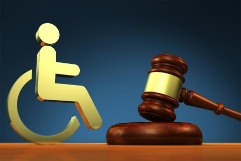 Symbol osoby na wózku obok młotka sędziowskiego