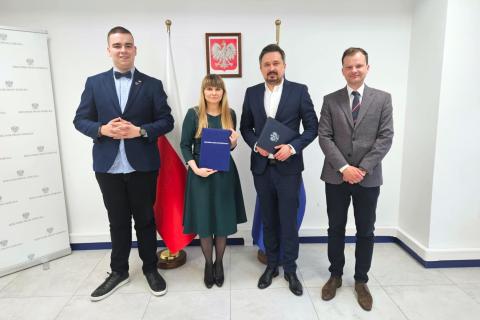 Cztery osoby pozują na stojąco do wspólnego zdjęcia