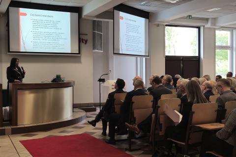 Zapełniona siedzącymi ludźmi aula. Przed miejscami siedzącymi znajduje się audytorium, przy którym stoi wypowiadająca się pełnomocniczka terenowa RPO Aleksandra Wentkowska.