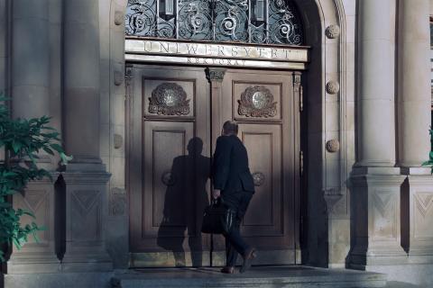 dwie osoby wchodzą do budynku z napisem rektorat uniwersytetu