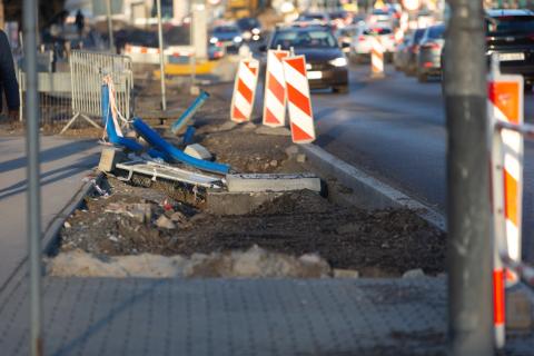 Rozkopany chodnik wzdłuż ulicy z widoczną studzienką telekomunikacyjną
