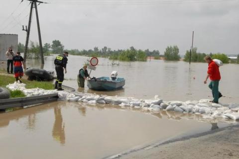 osoby układają worki z piaskiem podczas powodzi 