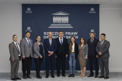 Dziewięć osób pozuje do zdjęcia na tle ścianki z logiem Rzecznika Praw Obywatelskich