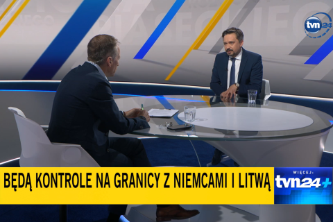 Dwie osoby siedzą w studiu telewizji przy dużym stole