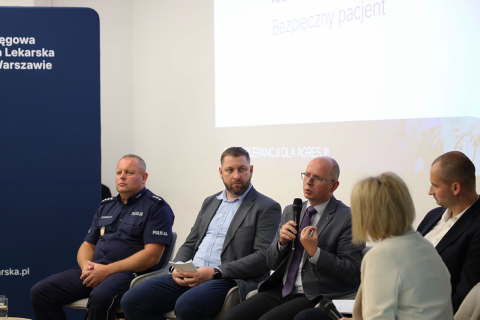 osoby siedzą w sali jedna przemawia