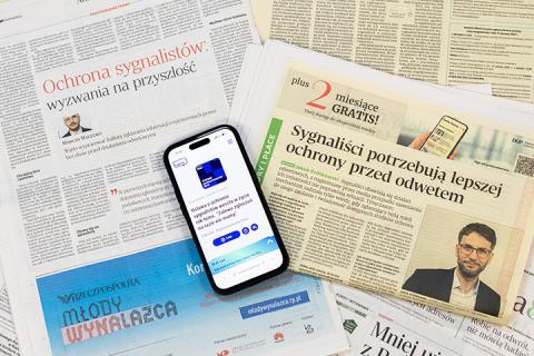 Otwarte gazety i smartfon z załadowaną stroną z wywiadem