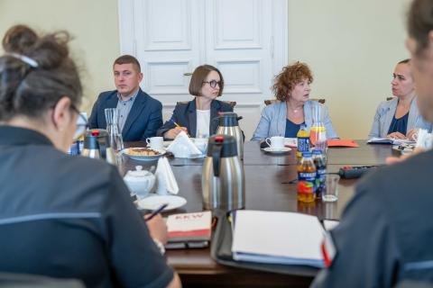 Sześć osób rozmawia siedząc przy stole konferencyjnym.