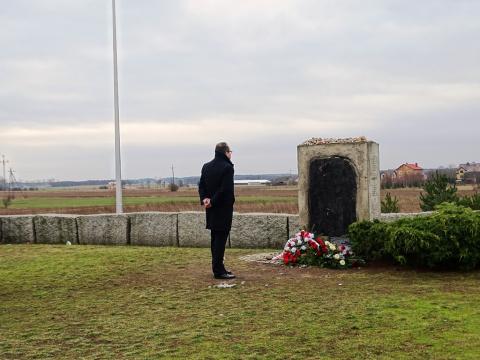 Mężczyzna przed pomnikiem, przed którym leżą kwiaty