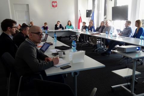 Zdjęcie: ludzie siedzą przy stole ustawionym w kztałcie litery U