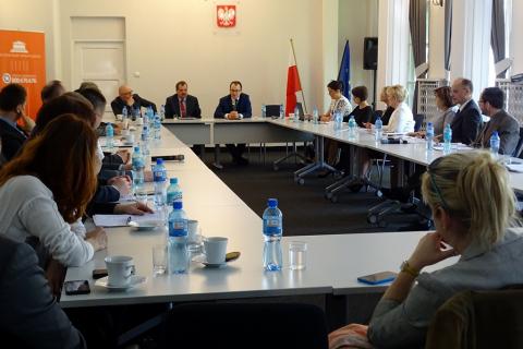zdjęcie: kilkanaście osób siedzi przy białych stołach ustawionych w prostokąt