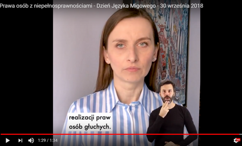 Screen z wystąpienia kobiety. na youtube. Na dole sylwetka tłumacza migowego  