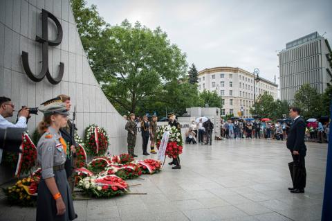 Osoba składa wieniec pod pomnikiem