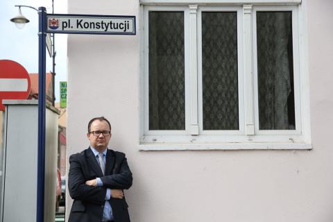 Mężczyzna pod domem z nampisem "Plac Konstytucji"