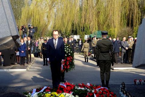 Mężczyzna stoi przed pomnikiem z pochyloną głową