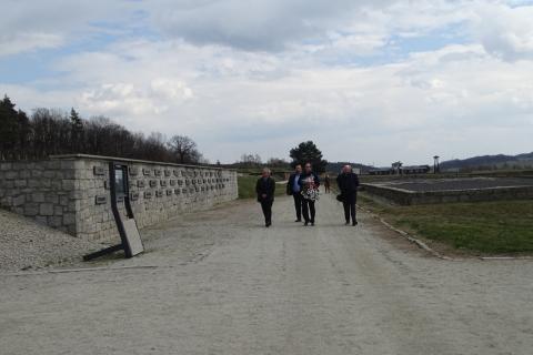 Grupa ludzi z kwiatami na terenie obozu koncentracyjnego