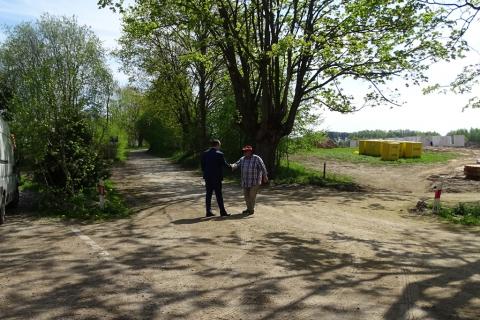 Dwaj mężczyźni na drodze witają się. jeden w roboczym ubraniu, drugi - w garniturze