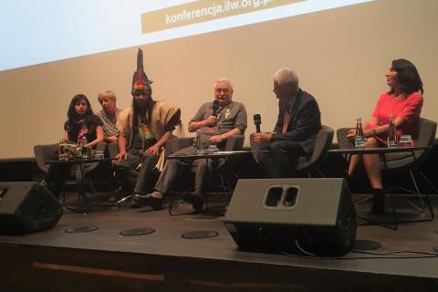 Uczestnicy panelu, w tym wódz w pióropuszu, siedzą ma scenie