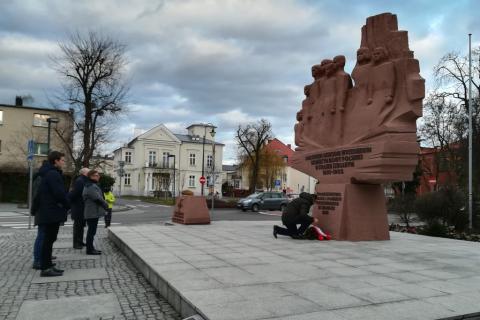 Mężczyzna kładzie wieniec pod pomikiem